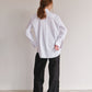 Person wearing a white shirt and black pants against a plain background